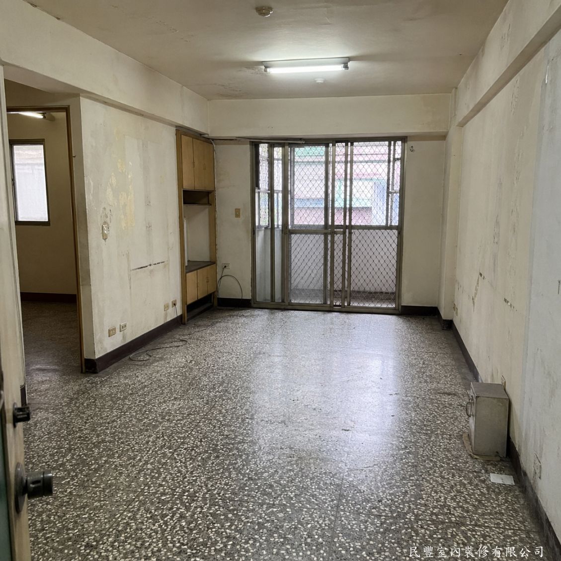 民豐室內裝修-客廳水電木作油漆地板暨浴室翻新-施工前客廳磨石子地板老舊，壁面嚴重汙損剝落，舊木作矮櫃過時，整體空間昏暗老舊。民豐師傅評估後確認全室翻新方案
