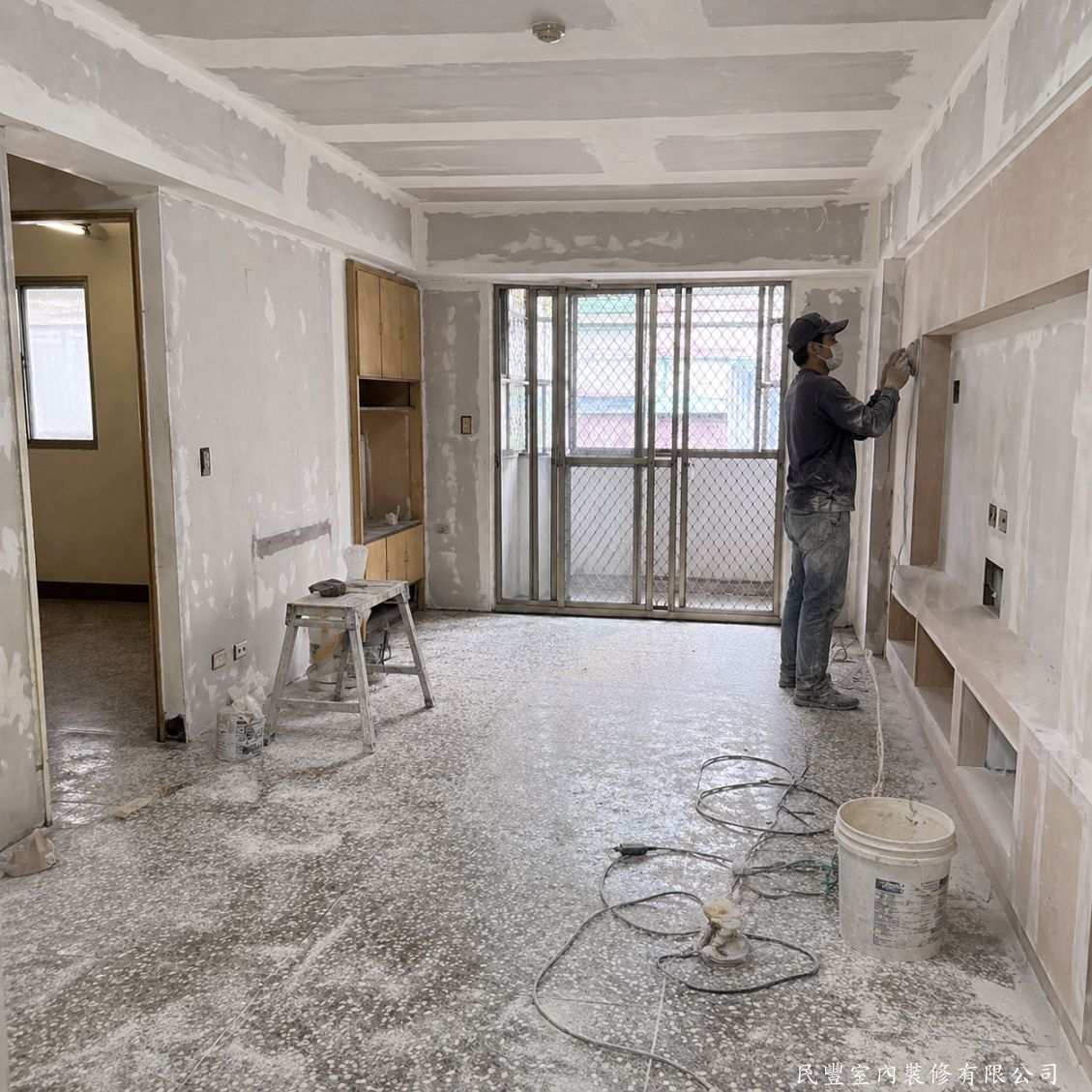 民豐室內裝修-客廳水電木作油漆地板暨浴室翻新-天花板矽酸鈣板封板批土完成，嵌燈孔位預留；同時電視木作牆格板骨架施作，師傅進行批土整平細部施工