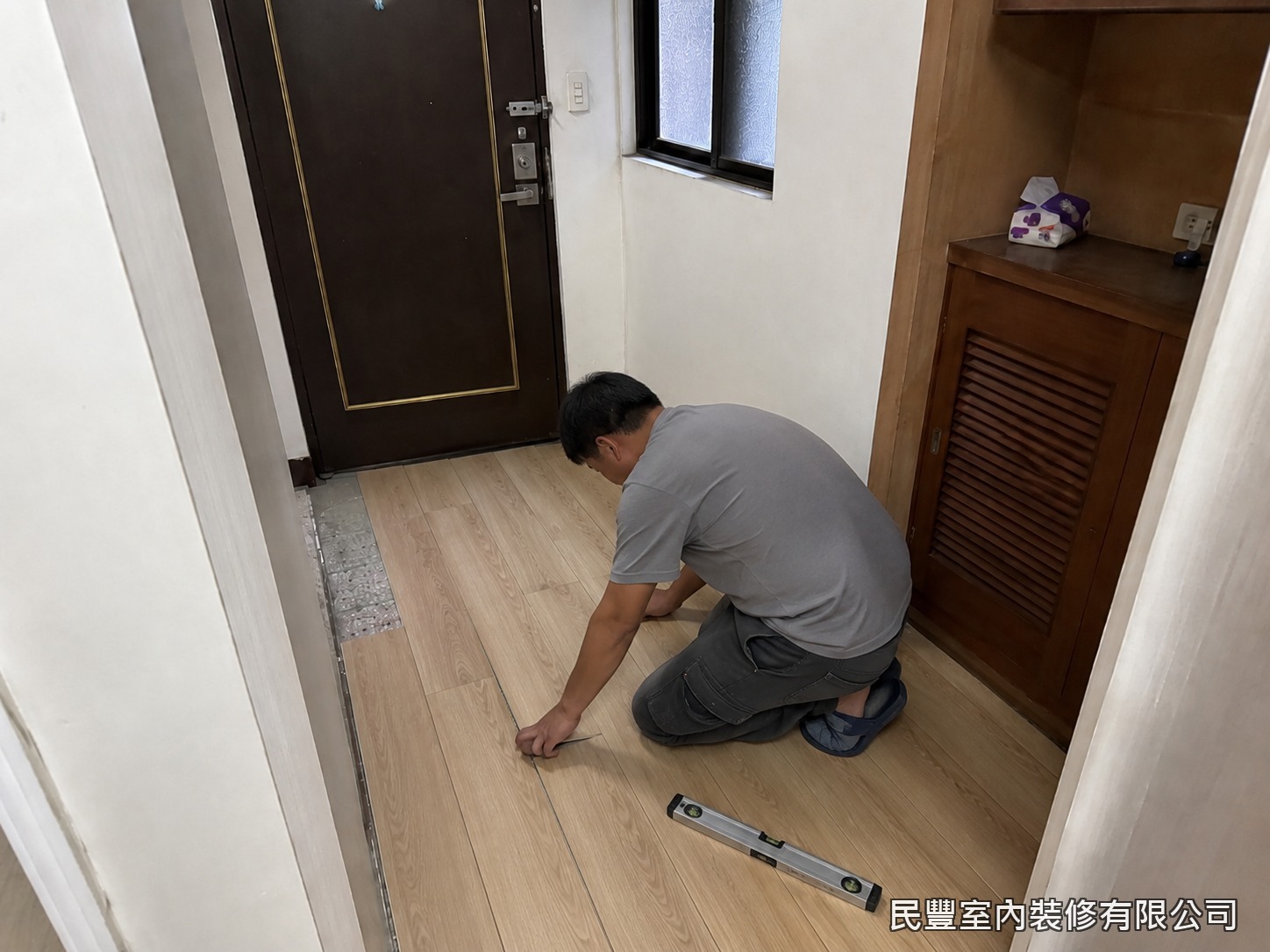 民豐室內裝修-SPC平鋪地板-師傅以卡扣平鋪工法逐片鋪設SPC石塑地板，水平尺隨時校驗，接縫緊密、面層平整