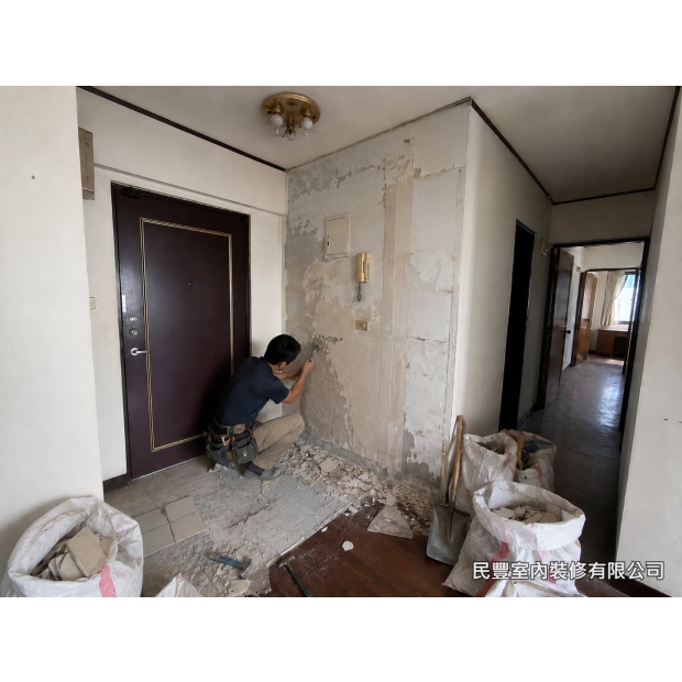 全室系統傢具裝修-師傅使用電動鑿除工具打除玄關舊磁磚，清理地面基底，為新磁磚鋪設做好準備，現場垃圾袋裝袋整齊，保持施工環境整潔有序