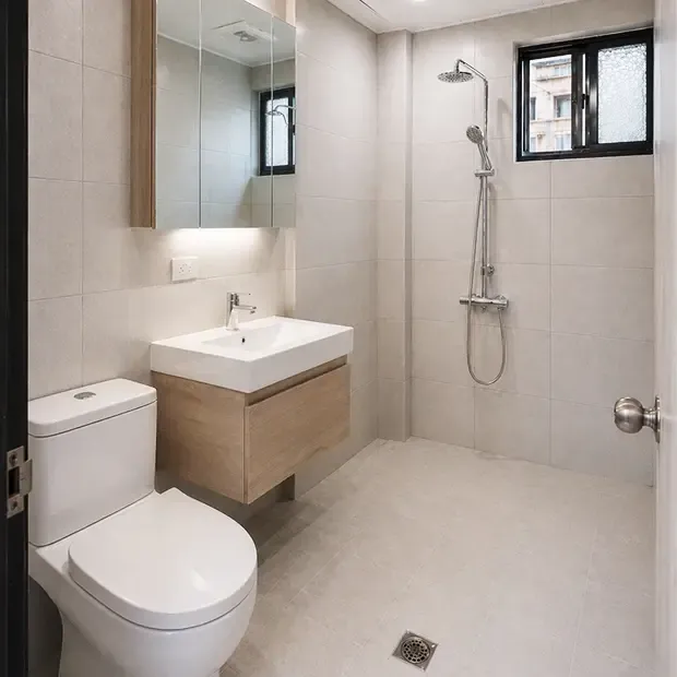 水電與防水工程-完工實景，完工後的浴室呈現現代簡約風格，淺色系磁磚搭配木紋洗手台與大面鏡櫃，空間明亮且收納充足。林先生對防水耐用度與整體質感非常滿意，全家每天使用都感受到生活品質的提升